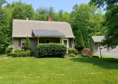 A house with a metal roof in the middle of a yard.