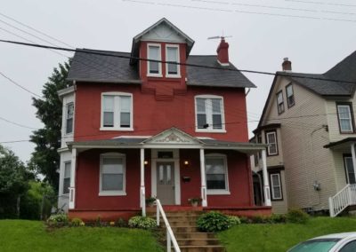 A red house with a black roof and white trim.