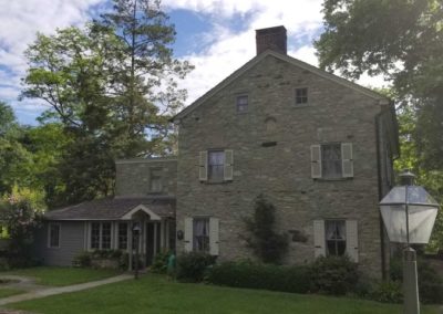 A large stone house with trees in the background.