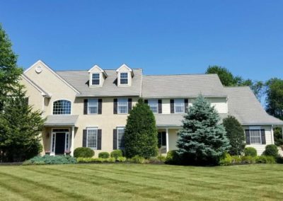 A large white house with a green lawn in front of it.