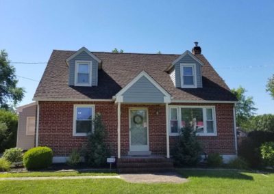 A brick house with a large lawn in front of it.