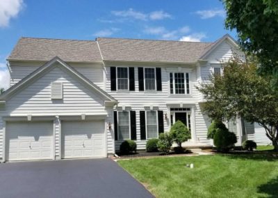 A large white house with black shutters and two garage doors.