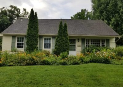 A house with bushes and flowers in front of it.