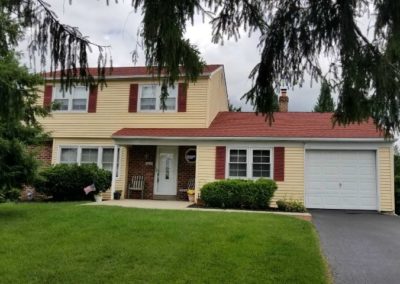 A yellow house with red shutters and white trim.