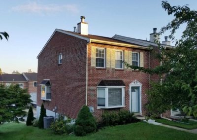 A brick house with a yellow door and window.