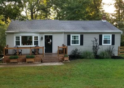 A house with a porch and lawn in front of it.