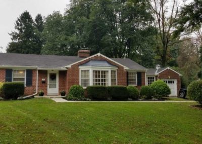 A brick house with a lot of green grass in front.