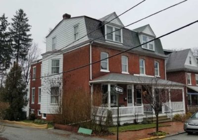 A large brick house with many windows and a porch.