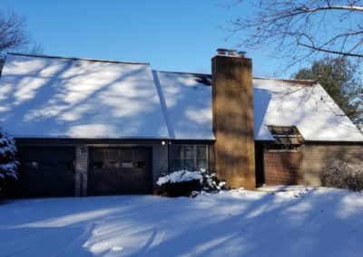 A house with snow on the roof and garage door.