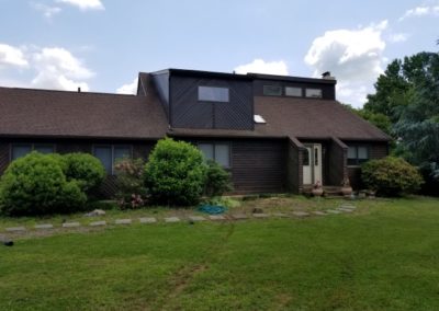 A large brown house with a green lawn in front of it.