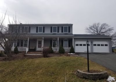 A large house with two cars parked in front of it.